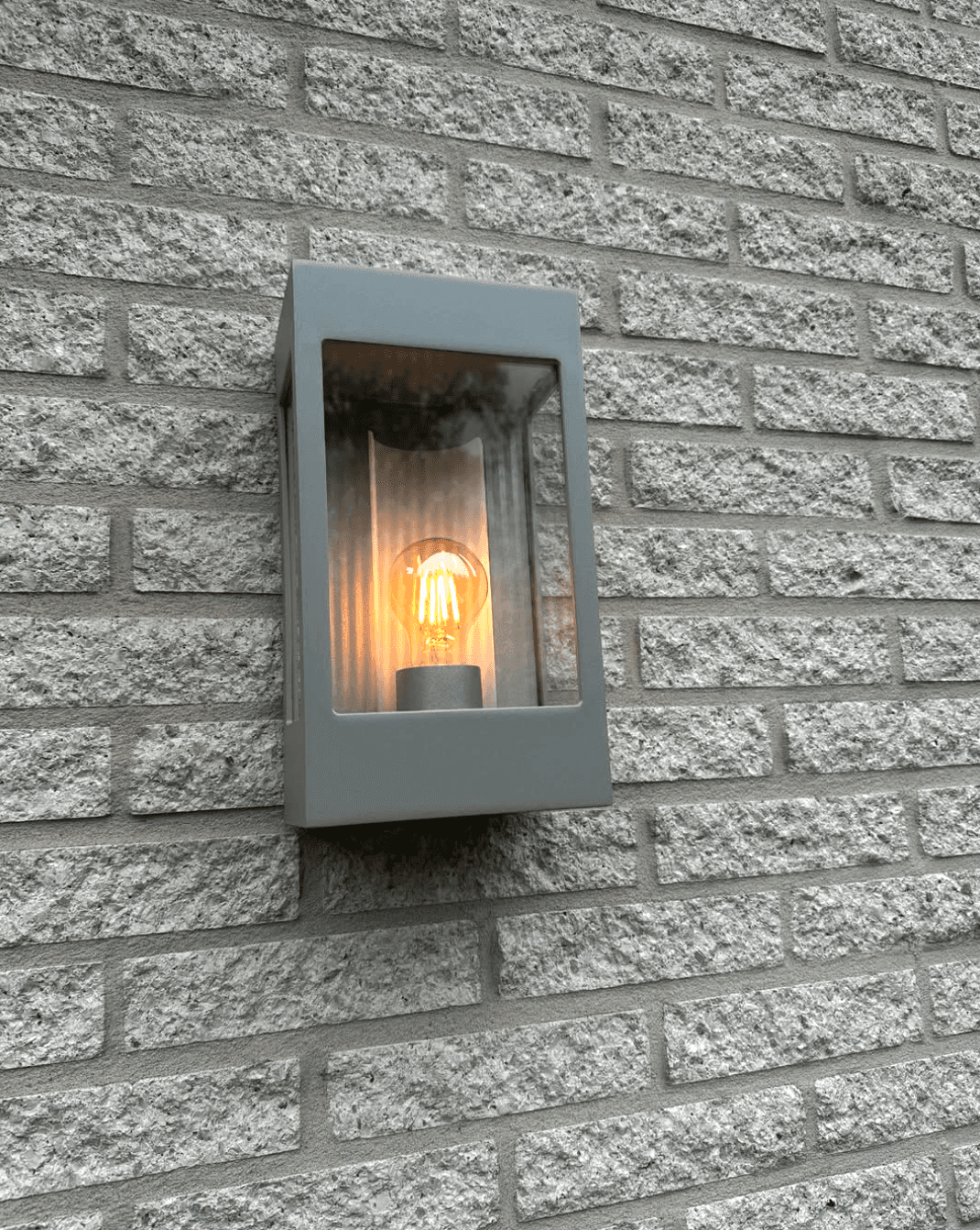 Buitenverlichting met wandarmatuur en filamentlamp tegen een bakstenen gevel