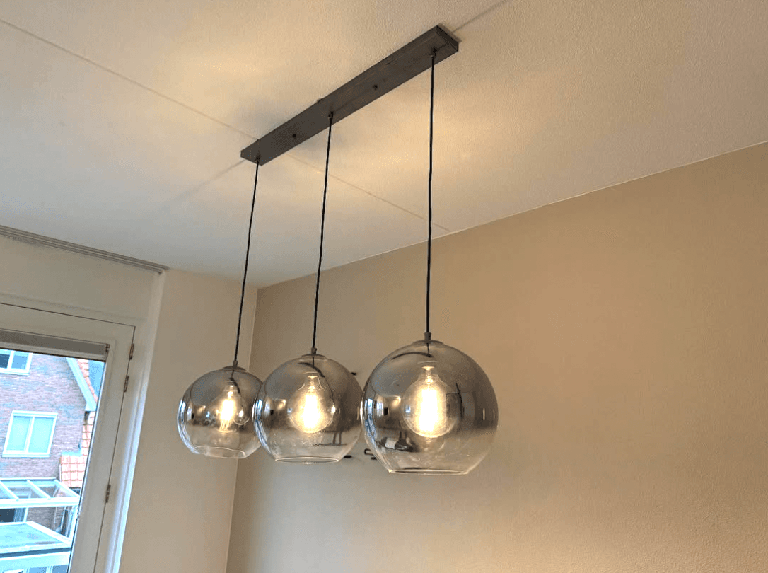 Hanglamp met drie bollen van rookglas boven een eethoek