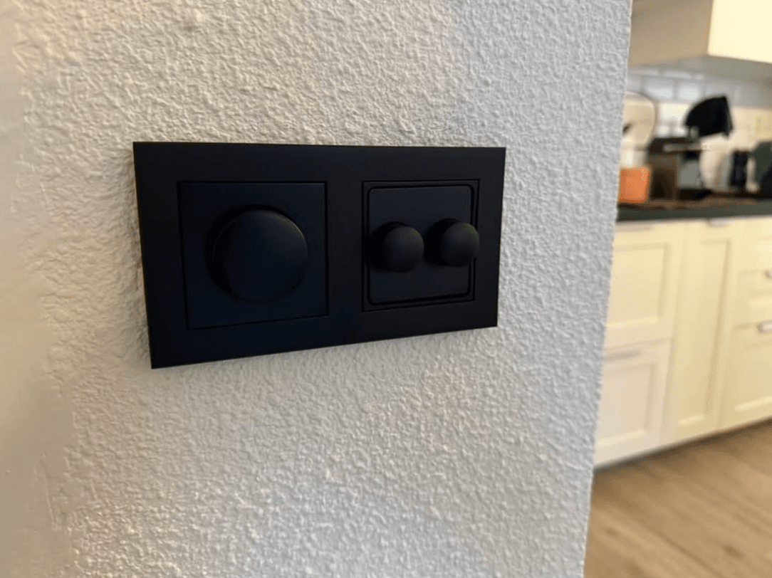 Strakke zwarte inbouwschakelaar en dimmer in een gerenoveerde keuken